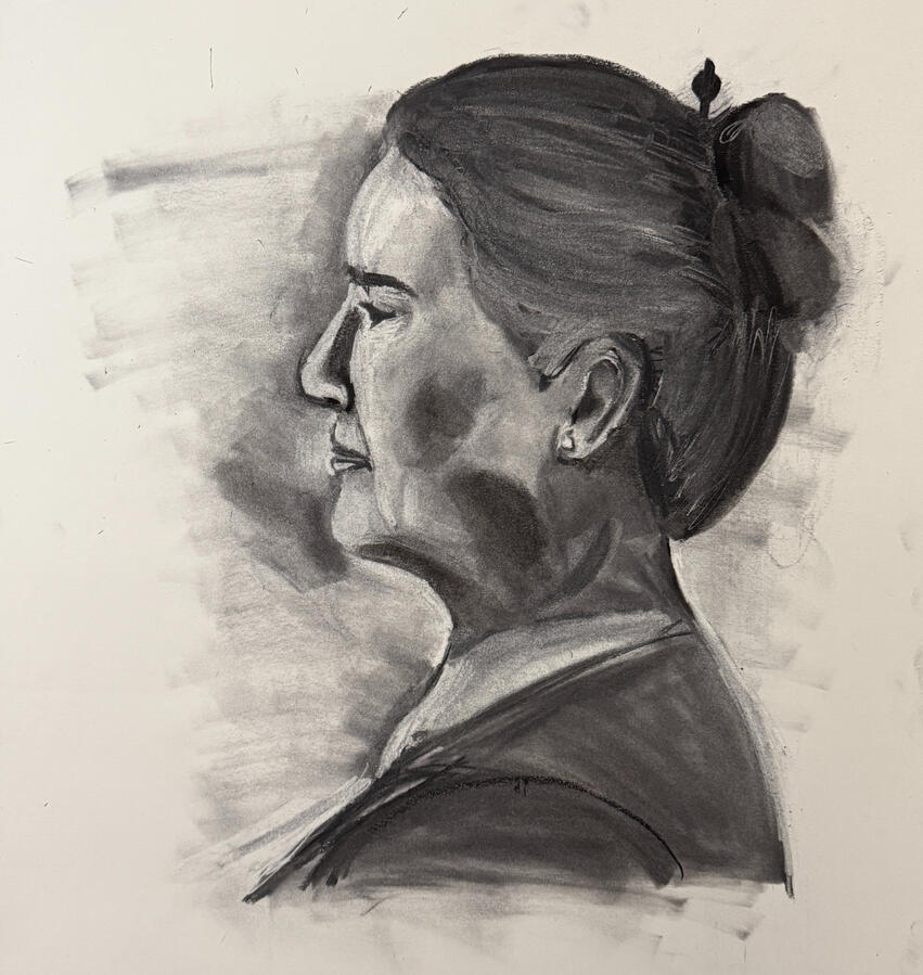 Charcoal portrait of a woman in profile, depicting her from the neck up with a high bun and a dark top. Her facial features include a prominent nose, closed eyes, and a small earring.