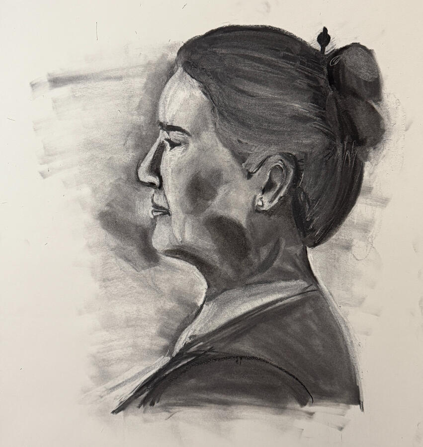 Charcoal portrait of a woman in profile, depicting her from the neck up with a high bun and a dark top. Her facial features include a prominent nose, closed eyes, and a small earring.